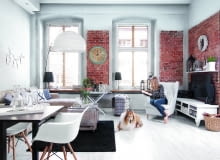 Duże okna szkoda było ukrywać za zasłonami, gospodarze wybrali więc żaluzje, które dobrze chroniąc przed słońcem, nie przesłaniają urody okien. Kanapa i fotel (ulubione miejsce Kasi i kotów) są z IKEA. Szafka pod telewizorem została 'stuningowana' - gospodyni pomalowała ją na biało i przykręciła nóżki z targu staroci. Pojemnik na koce (pod oknem) to znaleziony w piwnicy stary metalowy kosz na butlę z winem.