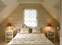 Sypialnia znajduje się na poddaszu. We wnętrzu, wystylizowanym na wiejskie, panuje sielska, pełna spokoju atmosfera. Ponieważ pomieszczenie nie jest duże, wstawiono tylko niezbędne meble: łóżko, szafki nocne oraz - niewidoczną na tym zdjęciu - sporą komodę. WNETRZA - SYPIALNIA , MEBLE