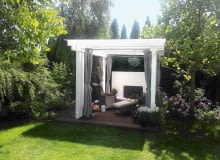 Altana ze ścianą wodną z tyłu to idealne miejsce do wypoczynku. Została ulokowana w głębi ogrodu, w sąsiedztwie kwitnących hortensji i okazałego tulipanowca.