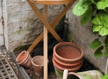 Mycie donic. Donic glinianych można używać wielokrotnie, ale wcześniej trzeba je wyczyścić i zdezynfekować Wooden Table with Cut Flowers and Garden String with Terracotta Plant Pots and Geranium Foliage (Pelargonium)