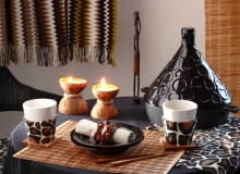 Dekoracje. Z tkaniny w lamparcie cętki lub pasy zebry (końcówki kuponów można kupić na wyprzedażach w sklepach) robimy bieżnik oraz pokrowce na poduszki leżące na krzesłach. Oklejamy nią także pasy sztywnej tektury, z której formujemy osłonki na kubki. Obrączki na serwetki to drewniane koraliki nanizane na cienką gumkę. Jeszcze tylko kokosowe świeczniki i goście mogą siadać do stołu! Materiały i narzędzia: orzech kokosowy, gruby sznur konopny, klej uniwersalny, biała świeca lub wosk, sznurek na knot, emaliowany rondelek, piłka do metalu, nożyczki, nitka, szpilka WNETRZA DEKORACJE NAKRYCIE STOLU