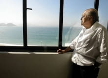Brazilian architect Oscar Niemeyer looks at the Copacabana beach from his office after his interview with Reuters in Rio de Janeiro, in this June 16, 2003 file photo. Niemeyer, a towering patriarch of modern architecture who shaped the look of contemporary Brazil and whose inventive, curved designs left their mark on cities worldwide, died late on December 5, 2012. He was 104. Niemeyer had been battling kidney and stomach ailments in a Rio de Janeiro hospital since early November. His death was the result of a lung infection developed this week, the hospital said, little more than a week before he would have turned 105. REUTERS/Sergio Moraes/Files (BRAZIL - Tags: OBITUARY SOCIETY)