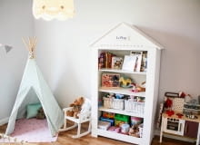 W pokoju dziewczynki został ustawiony mały namiot, w którym uwielbia się bawić swoimi misiami i lalkami. Obok stoi regał w kształcie domu. Pokjó dziecięcy, meble dziecięce, pokój dziewczynki, zabawki