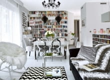 Wszechobecna biel: w tym kolorze są ściany, podłogi i większość mebli; właściciele przemalowali nawet pianino! Na takim neutralnym tle dobrze prezentuje się kolekcja książek, płyt i obrazów. Żyrandol, kupiony w jednym z marketów budowlanych, w innym wnętrzu mógłby wydać się pretensjonalny. Tu świetnie pasuje do stylizowanego stołu (IKEA) oraz srebrzystych krzeseł w stylu glamour. Głównym bohaterem salonu jest zrobiona na zamówienie biblioteczka. Boczne półki są ścięte, dzięki czemu tworzą spójną całość ze skośną ścianą.