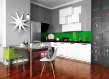 Kuchenną zabudowę z jednej strony ogranicza ściana z przewodem kominowym (za nim ukryto wolno stojącą lodówkę i piekarnik z płytą grzejną), z drugiej strony zwykła szafa. Jej front pomalowano czarną farbą tablicową, z czego - jak widać - z radością korzysta Franek, syn gospodarzy. Nad płytą grzejną zainstalowano okap wertykalny. Na podłodze - egzotyczne drewno merbau. To gatunek na tyle twardy i wytrzymały, że sprawdza się również tuż przy szafkach, czyli w miejscu, gdzie posadzka jest najbardziej narażona na uszkodzenie. Kuchnia, wystrój kuchni, meble kuchenne