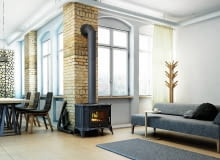 Piec ustawiony w centralnej części salonu, który jest otwarty na pozostałą część domu, w efekcie ciepło rozchodzi się do pomieszczeń znajdujących się w pobliżu kozy