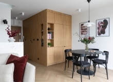 Ściana i zabudowa meblowa we wspólnym wykończeniu drewnem tworzą atrakcyjną, zwartą, architektoniczną formę – swego rodzaju kubik. Skrywa on łazienkę, lodówkę oraz szafę do przechowywania. Ściana i zabudowa meblowa we wspólnym wykończeniu drewnem tworzą atrakcyjną, zwartą, architektoniczną formę – swego rodzaju kubik. Skrywa on łazienkę, lodówkę oraz szafę do przechowywania.