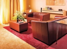 Salon. Kontrastowe barwy dwóch wykładzin dywanowych nawiązują do kolorystyki całego wnętrza. Do aneksu wypoczynkowego wybrano czerwoną; taki kolor ma też sufit podwieszany i klosze wiszących lamp. WNETRZA , POKOJ , SALON , PODLOGA - WYKLADZINA DYWANOWA