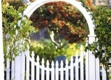 Ro-man-tycz-na bram-ka po-łą-czo-na z pod-po-rą dla pną-cej ró-ży zo-sta-ła per-fek-cyj-nie za-pro-jek-to-wa-na i wy-ko-na-na, tak jak i całe ogrodzenie. Drewniana furtka z pergolą