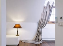 <B>Nocą do tej sypialni zaglądają tylko gwiazdy, nie ma więc potrzeby szczelnego zasłaniania małych okien. Wiszące tu zasłony mają inne zadanie - zdobienie wnętrza. I wywiązują się z niego znakomicie.</B> </BR> Do udrapowanej na stałe tkaniny, ścielącej się po podłodze, doszyto troczki z haczykami, które zaczepia się na&#8200;gałkach przymocowanych do&#8200; ściany nad&#8200;oknem. Takich&#8200;samych gałek użyto do&#8200;podpięcia zasłon. Taka&#8200;aranżacja wygląda nieco teatralnie, ale&#8200;efektownie.