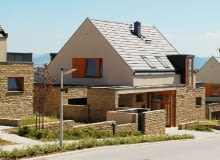 Osiedle domów jednorodzinnych - kamień na parterze, tynk na piętrze i powtarzające się drewniane elementy stolarki okiennej i drzwiowej Osiedle domów jednorodzinnych - kamień na parterze, tynk na piętrze i powtarzające się drewniane elementy stolarki okiennej i drzwiowej