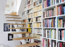 POD SKOSEM. Bardzo pojemna biblioteczka została ulokowana przy schodach prowadzących na antresolę. Półki zaprojektowano pod wymiar książek. Półki na książki warto zaprojektować pod swoje zbiory. Jeśli mamy dużo albumów - część z półek powinna być wyższa i głębsza niż standardowe. Najmniej będą przeszkadzały, jeśli umieścimy je na samej górze biblioteczki. OSous et sur les toits, larchitecte Philippe Chiambaretta et sa femme leditrice Julie Rouart rcgnent au sommet dune joyeuse tribu. Dans cet espace retranche, cerne de verdure, lart, les livres et les lignes campent une humeur dilettante o? pavoise le go?t de la creation.--Gros plan sur limmense bibliothcque montant jusquau toit.