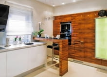 Nietrudno urządzić nowoczesną kuchnię, bo wybór mebli i materiałów jest ogromny. Czy jednak, tak jak się na ogół uważa, musi być ona sterylna jak laboratorium? Wcale nie. Zobacz wnętrza, które prezentujemy. <BR > Aranżacje wnętrz. W tej kuchni jedna ze ścian wygląda tak, jakby niemal cała została zabudowana szafkami. W rzeczywistości wnękowa zabudowa z frontami fornirowanymi palisandrem jest mniejsza - fragment ściany po prawej stronie został obłożony identycznie wykończonymi panelami (palisandrem jest też fornirowany barek). Na panelach zamocowano płytką szklaną szafkę. WNETRZA , KUCHNIA - BAREK , CIAG KUCHENNY Z EKSPRESEM DO KAWY , PIEKARNIKIEM , LODOWKA STYLIZACJA DOROTA KARPINSKA FOT. RAFAL LIPSKI PUBLIKACJA CZTERY KATY NR 6 (236) - 6 2011 SLOWA KLUCZOWE: WNETRZE KUCHNIA ARTYKULY GOSPODARSTWA DOMOWEGO ZDJĘCIE DO WKŁADKI: PUBLIKACJA CZTERY KATY NR 6 (236) - CZASOPISMA