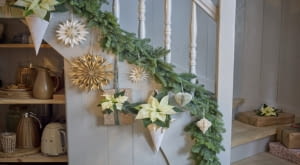 Kremowo-białe poinsecje, zarówno cięte, jak i doniczkowe, zdobią balustradę i prezenty.