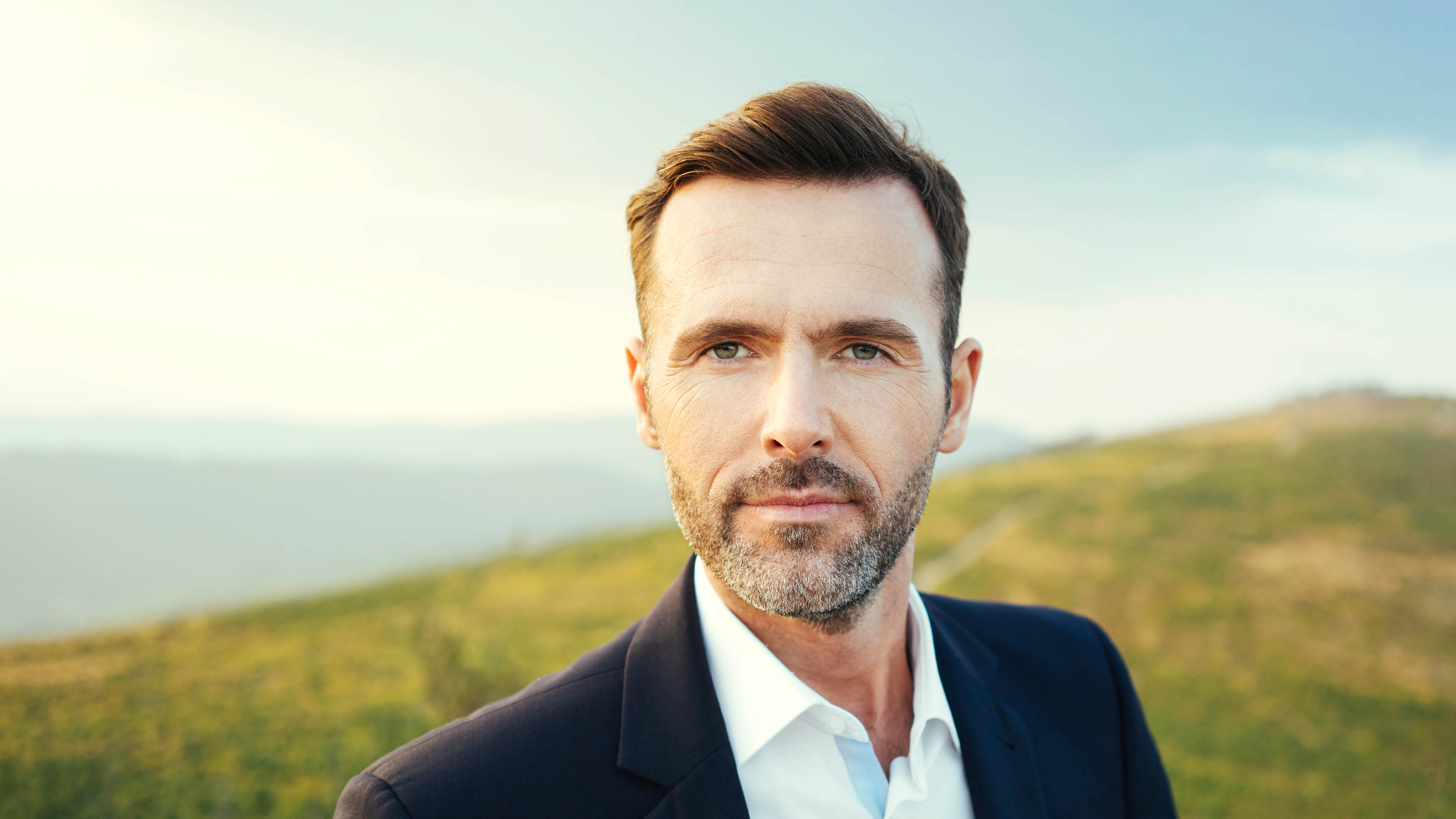 Portrait of self-confident businessman  on top of a mountain