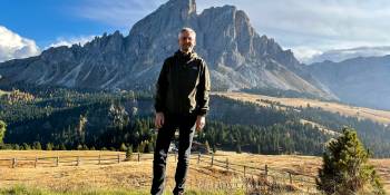 Blogger Raymond Geurtsen in een groene alpenweide in wandelkleding. Op de achtergrond de berg Sass de Putia onderdeel van de Dolomieten aan de Passo delle Erbe in Val Badia Zuid-Tirol.