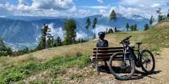 Fietser op bankje met mountainbike uitkijkend over de Valsugana vallei in Trentino Italië