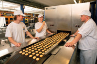 Lernende im Backwarentechnikum prüfen am Ofenausgang die frisch gebackenen Plätzchen Qualitätskontrolle inklusive Probieren.