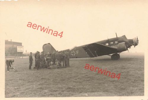 Deutsche Soldaten vor Flugzeug Junkers Ju 52 mit Kennung auf Flugplatz