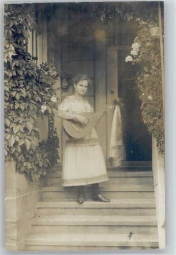 Frau mit einer Laute steht vor dem Haus