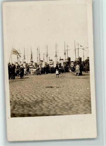 Menschen strömen zum Hafen, dort liegen Kriegsschiffe