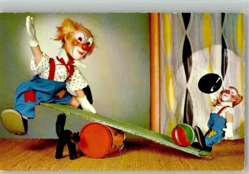 Zwei Clownspuppen und Katze auf einer Wippe