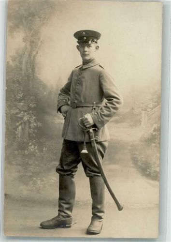 Ein junger deutscher Kavallerist in Uniform mit Schirmmütze Säbel und Reitstiefeln Fotostudioaufnahme