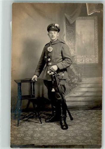 Deutscher Kavallerist in Uniform mit Säbel Schirmmütze und Blumenschmuck im Fotostudio