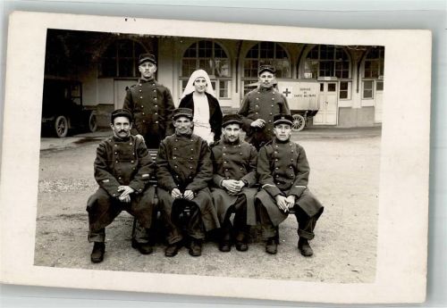 Krankenschwester inmitten von Soldaten in Uniform vor einem Automobil vom Roten Kreuz WK I