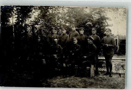 Gruppenaufnahme von Offizieren in Uniform mit Feldmützen in einer Waldstellung