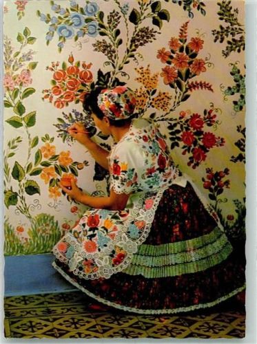 Frau in bunter Tracht aus Kalosca bemalt eine Wand mit Blumen Fotograf Gink Karoly