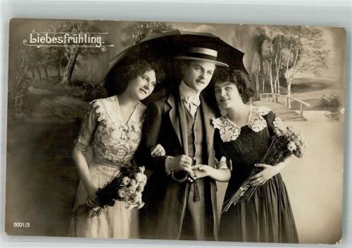 Eleganter junger Mann mit zwei Frauen unter dem Regenschirm
