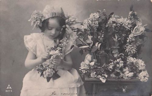 Ein junges Mädchen in einem hellen Kleid, das Blumen hält und sitzt.