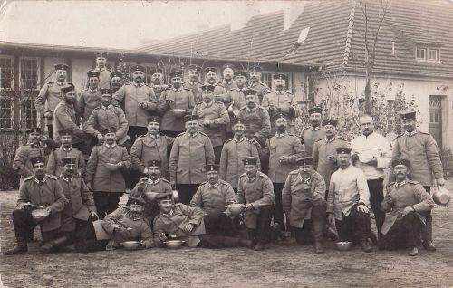 Gruppe deutscher Soldaten, möglicherweise Reservisten oder Landwehr, die während des Ersten Weltkriegs eine Mahlzeit einnehmen.