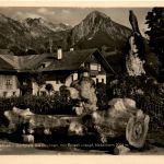 Partie aus Fischen, Dorfplatz mit Brunnen und Berge