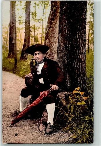 Junger Mann mit Schirm und Pfeife im Wald sitzend