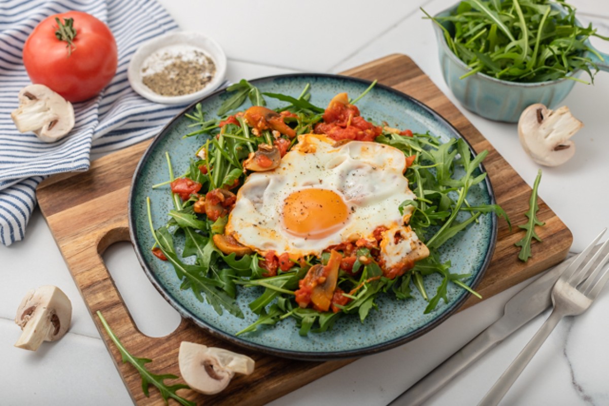 Egg on tomatoes with mushrooms and rocket