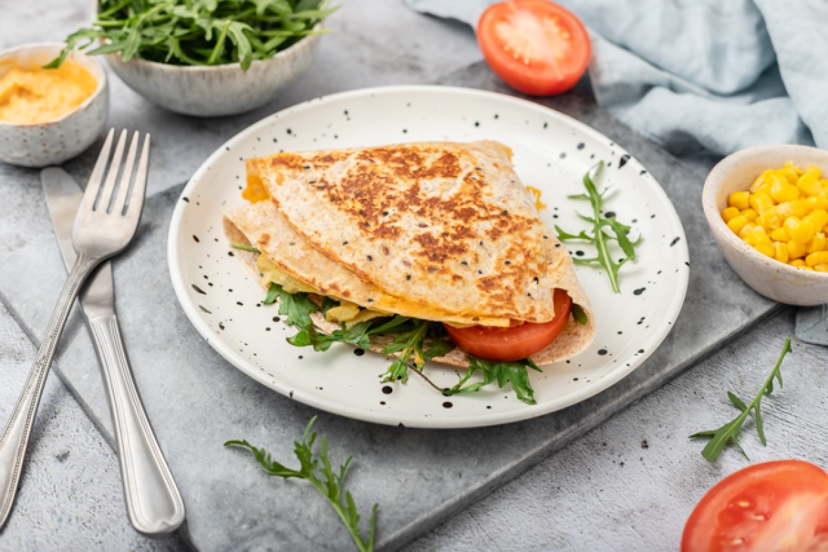 Vegetarian tortilla with hummus, cheddar, rocket and tomato, served warm