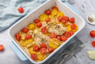 Roast chicken with potato slices, cocktail tomatoes and onion