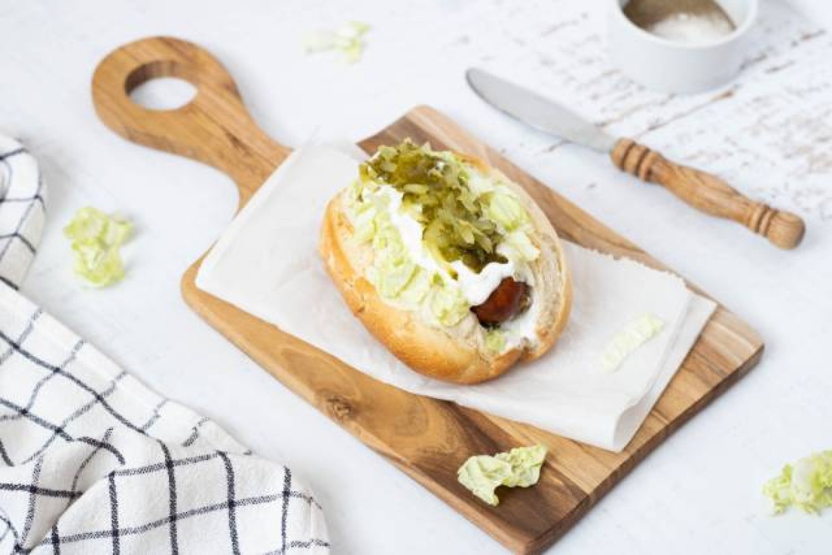 Hot dog with sausage, Chinese cabbage and pickled cucumbers