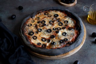 Black pizza with tomatoes, mozzarella, and olives