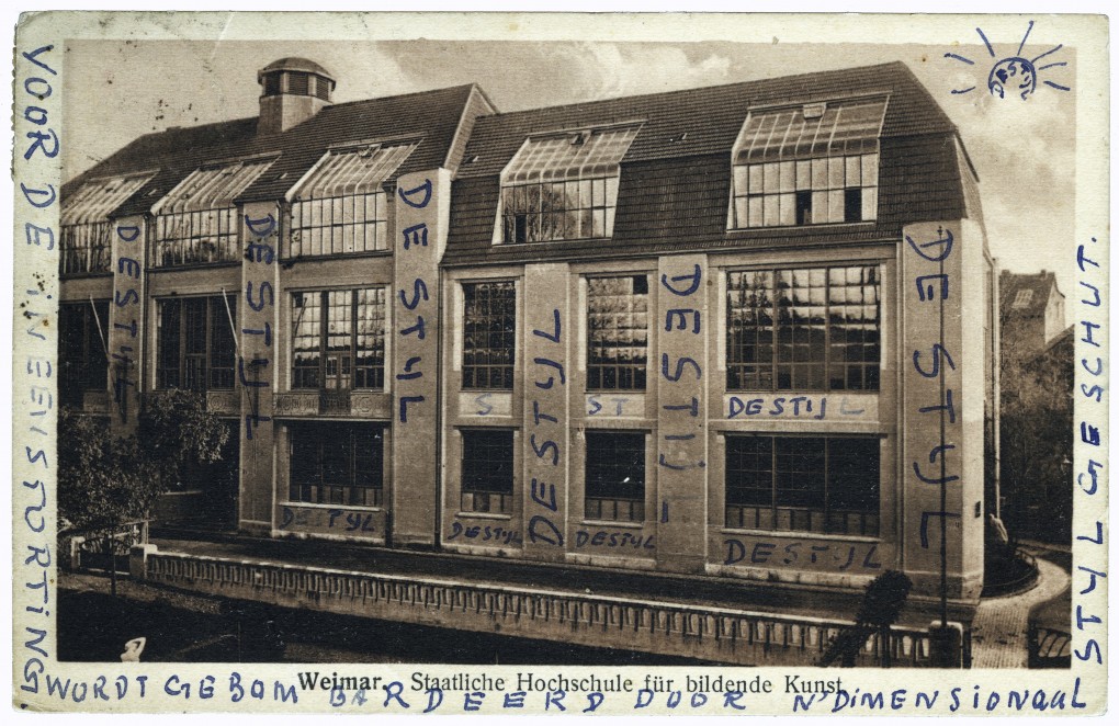 Ansichtkaart van het Bauhaus in Weimar, door Theo van Doesburg voorzien van de tekst: (links) voor de ineenstorting, (onder) wordt gebombardeerd door n’dimensionaal, (rechts) Stijl geschut, 21 september 1921, verzonden aan zijn vriend Anthonie Kok. RKD – Nederlands Instituut voor Kunstgeschiedenis, Den Haag (archief Theo en Nelly van Doesburg).