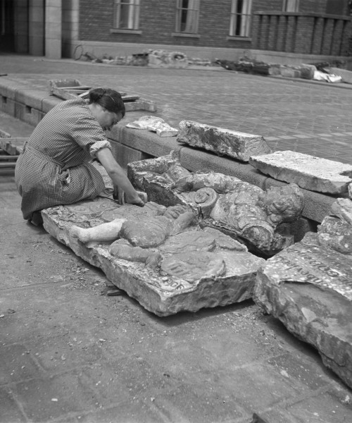 View of miss W.A.H. Crol exploring the remains of works of art (sculptures) in the courtyard of Museum Boymans, 1940. Source: Stadsarchief Rotterdam.