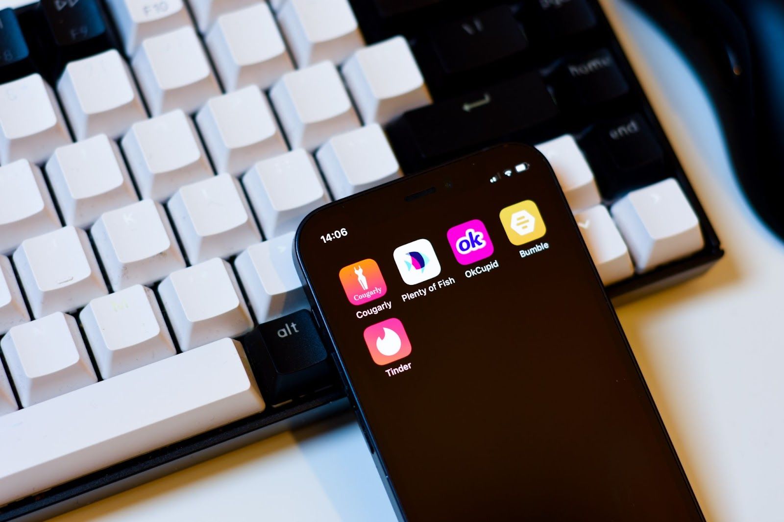 Ein iPhone liegt auf einer Tastatur und zeigt die Dating-App-Icons Plenty of Fish, OkCupid, Bumble, Tinder und Cougarly.