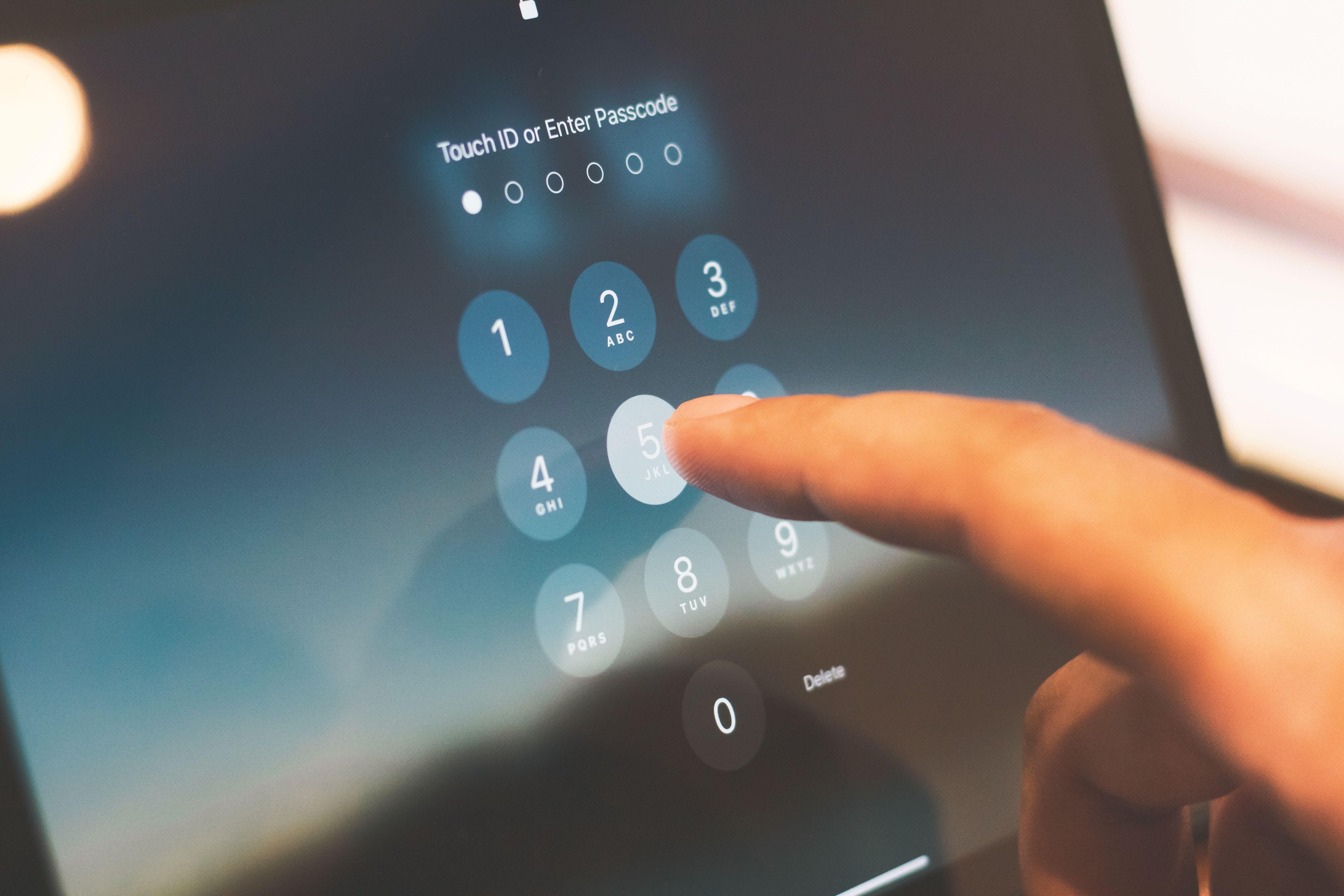 Close-up of a finger entering a passcode on a smartphone security screen