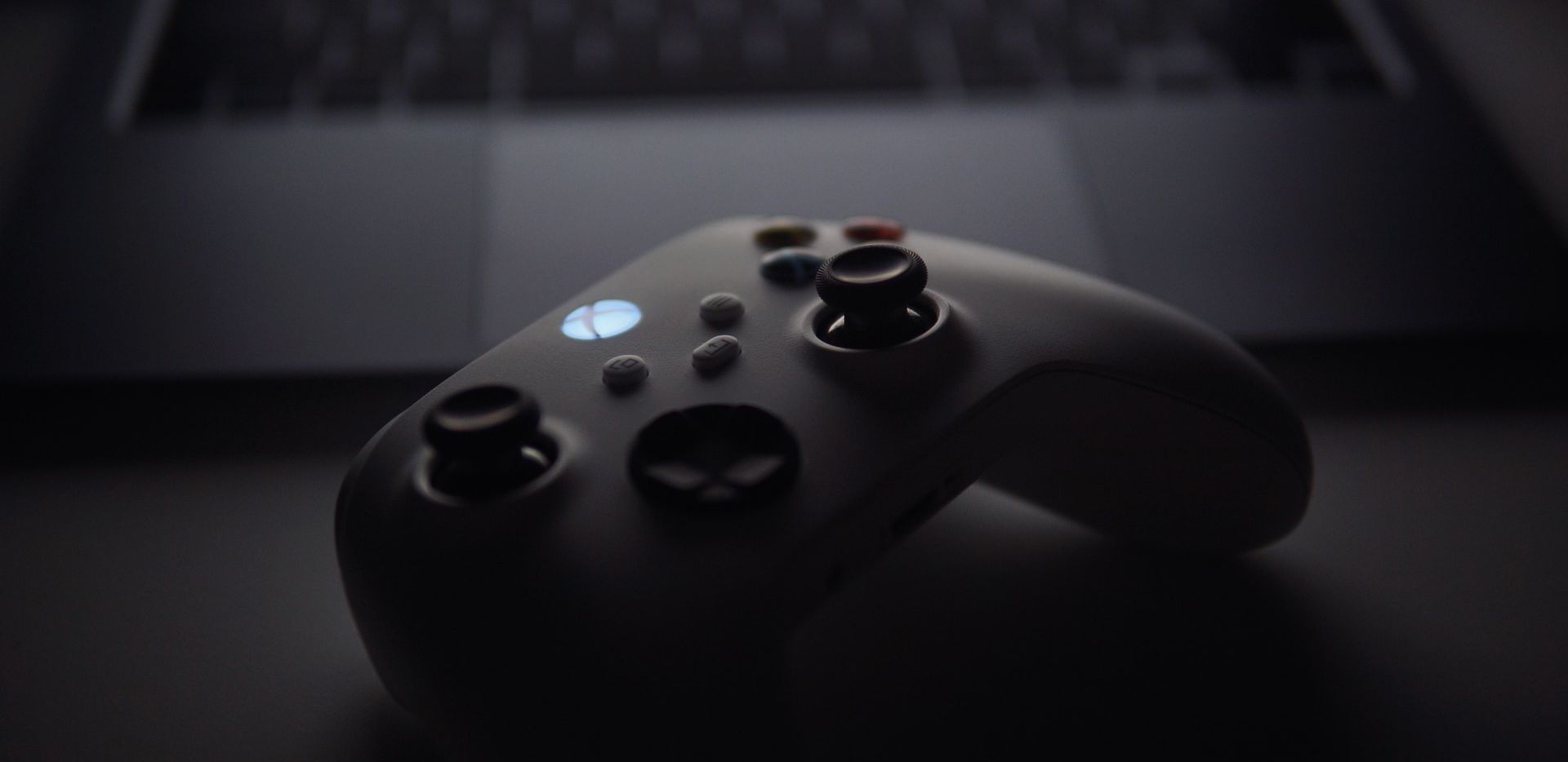 Dunkles Foto eines Xbox-Controllers vor einem Laptop. 