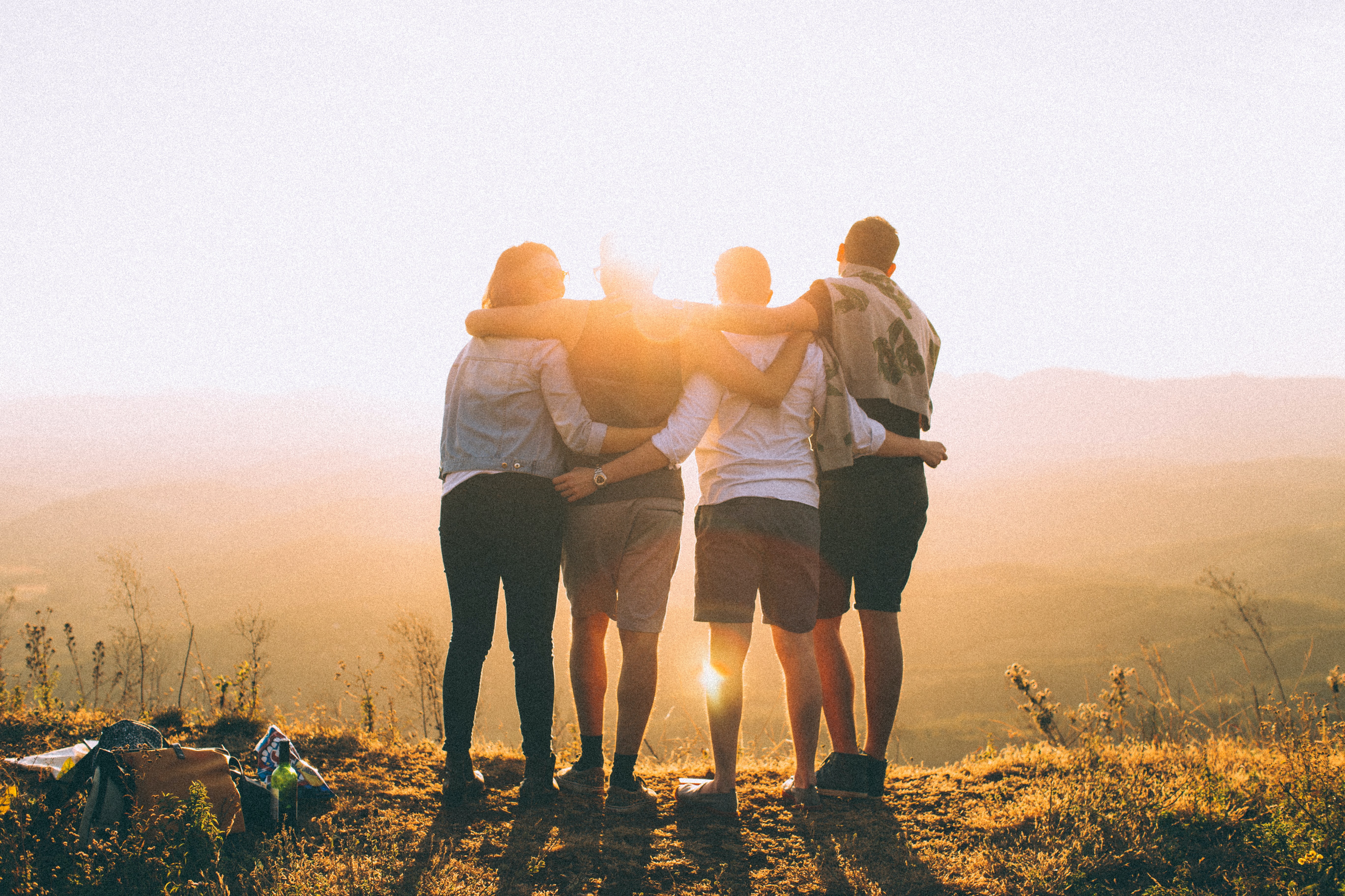 Sociological Theories of Religion, Four friends hugging while facing a sunset, StudySmarter
