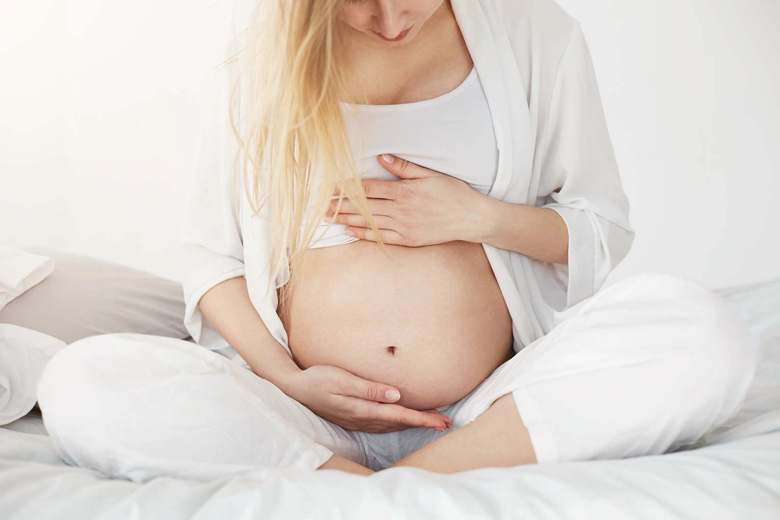 Evolution and Behavior, mother holding pregnant belly on bed, 91Ó°ÊÓ