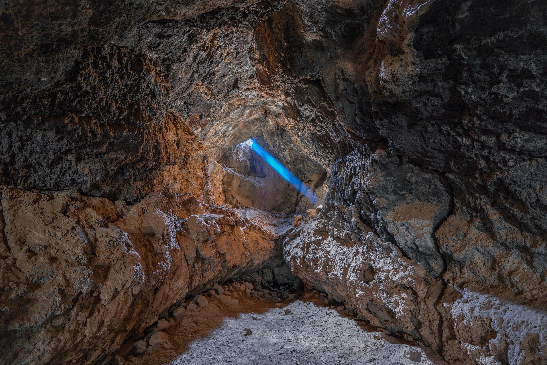 Methodology. A sunbeam shoots through a cave. StudySmarter.