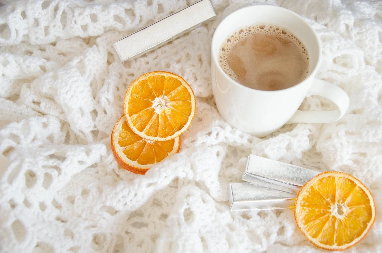 Sunday Morning, A cup of Coffee and slices of tried oranges on a crocheted white blanket, StudySmarter